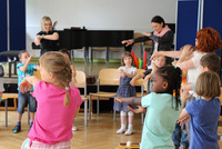 Auf dem Foto singen und tanzen Volksschüler/innen gemeinsam mit ihren Lehrerinnen.