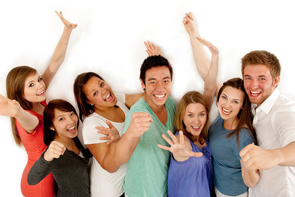 eine Gruppe junger Menschen, Männer und Frauen, verschiedener Hautfarben die in die Kamera lachen und die Hände in die Höhe halten.