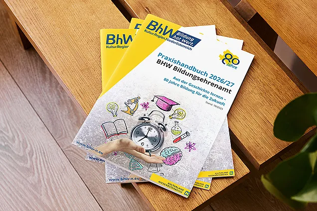 Das Bild zeigt aus der Vogelperspektive den Ausschnitt einer Holzbank. Auf dieser liegen mehrere Exemplare des neuen Praxishandbuchs Bildungsehrenamt.