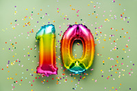 grüner Hintergrund mit Konfettis, im Vordergrund sieht man bunte aufgeblasene Luftballons in Form einer 10.