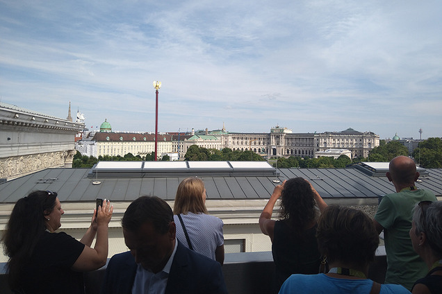 Die Bildungsgemeinderätinnen und Bildungsgemeinderäte stehen auf einem Balkon und fotografieren mit ihren Handys über den Dächern von Wien.
