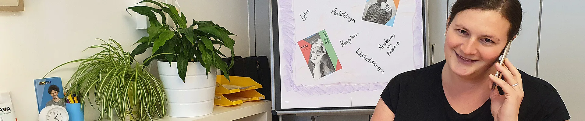 Bildungsberaterin Christa Sieder sitzt bei einem Tisch und telefoniert mit einer Rat-suchenden-Person und notiert sich etwas auf einem Schreibblock.