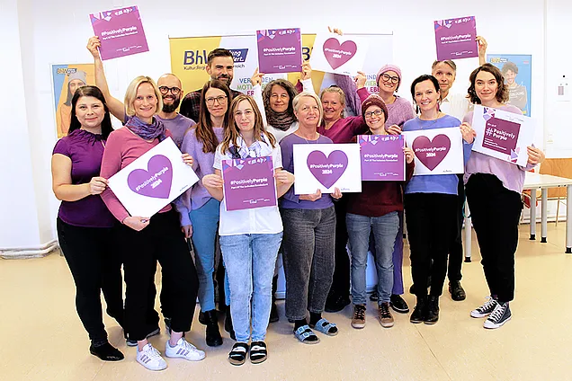 Das Team des BhW Niederösterreich, lila gekleidet, hält violette Schilder mit der Aufschrift „Positively Purple“