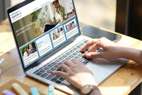 Aufgeklappter Laptop, auf dem Bildschirm sieht man die Startseite der Website "Bildungsangebote.at". Zwei Frauenhände tippen auf der Tastatur.