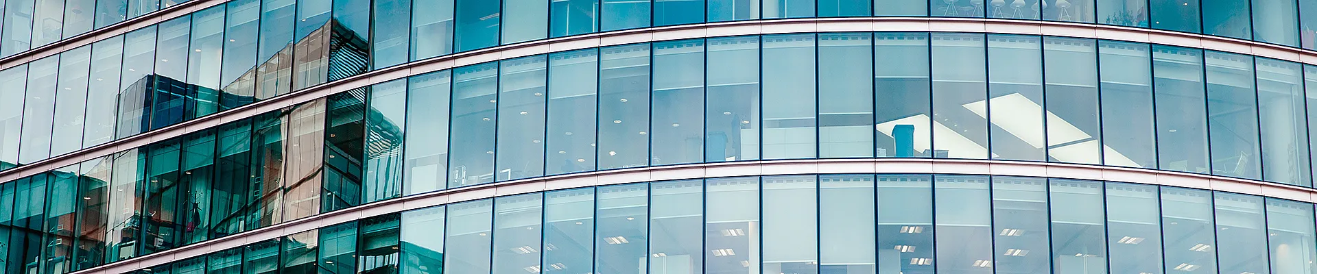 Auf dem Bild ist die abgerundete Glasfassade eines Hochhauses zu sehen, in dem sich weitere Hochhäuser spiegeln. Das Bild dient als Sinnbild für das Thema der beworbenen Veranstaltung.