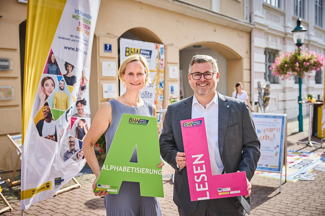 BhW Geschäftsführerin Therese Reinel und Landesrat Ludwig Schleritzko stehen mit großen Buchstaben vor dem BhW info-Point