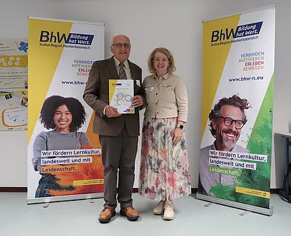 Foto mit 2 Personen, eine der Personen hält eine "80 Jahre BhW" Urkunde.
