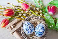 Auf einem Tisch liegen kleine Ratschen, Tulpen und Ostereier