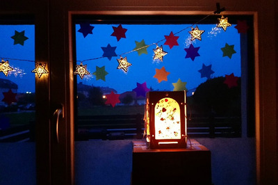 Weihnachtlich geschücktes Fenster mit Sternen und einer leutenden Laterne davor.