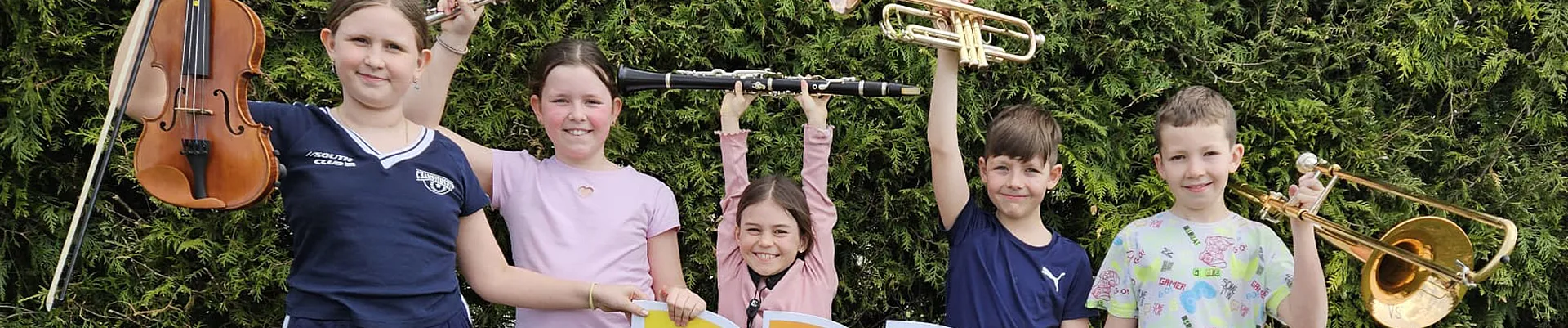 Gruppenbild mit Kindern die Instrumente hoch halten.