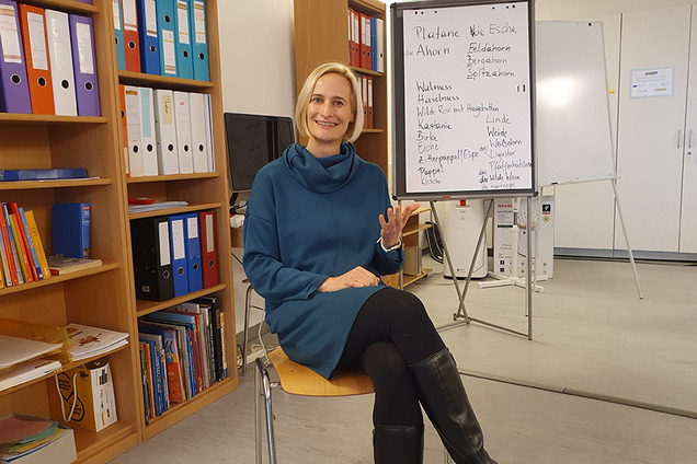 BhW Geschäftsführerin Therese Reinel sitzt in einem Schulungsraum vor einem Bücherregal und Flipchart und wird interviewt.