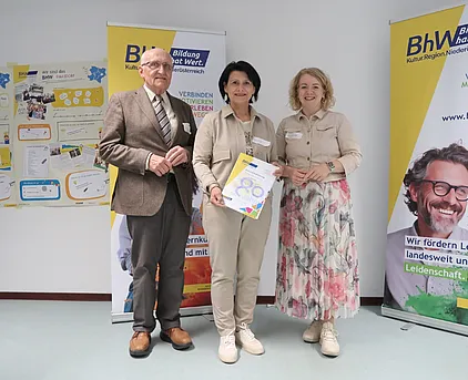 Foto mit 3 Personen, die Person in der Mitte hält eine "80 Jahre BhW" Urkunde.