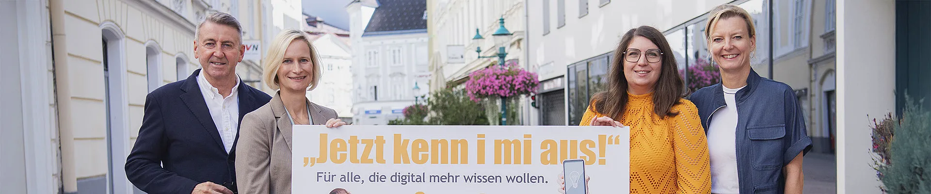 Auf dem Foto sind zu sehen: kabelplus-Geschäftsführer Wolfgang Schäffer, Geschäftsführerin des BhW Niederösterreich Therese Reinel, Smartphone-Trainerin Julia Hentschel und Geschäftsführerin des Burgenländischen Bildungswerks Judith Tscheppe. Sie alle halten eine Tafel mit der Aufschrift „Jetzt kenn i mi aus! – Für alle, die digital mehr wissen wollen“ zur Bewerbung von gemeinsam durchgeführten Online-Workshops zu Computer- und Smartphone-Themen. 