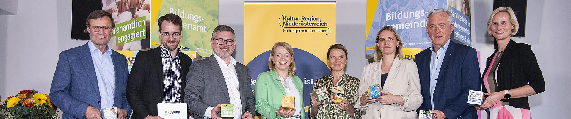 Gruppenbild mit den erwähnten Personen. Im Hintergrund große bunte Würfel mit BhW-Projektinfos und ein Roll der Kulturregion.