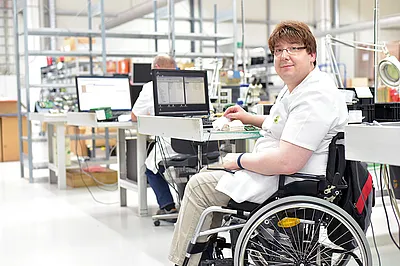 Ein Mann im Rollstuhl bei der Arbeit in einem Industriebetrieb.