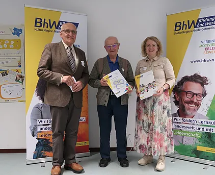 Foto mit 3 Personen, die Person in der Mitte hält eine "80 Jahre BhW" Urkunde.