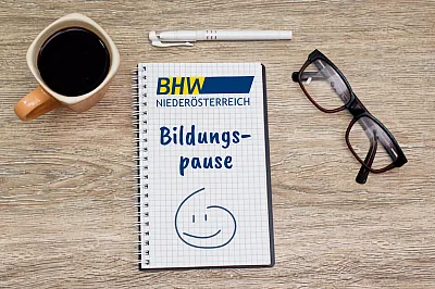 Das Bild zeigt einen Schreibtisch von oben. Darauf liegen ein Block und eine Brille, daneben steht eine Kaffeetasse.