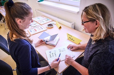 Eine Teilnehmerin der Basisbildung übt, gemeinsam mit einer Lernbeleiterin, das Schreiben.
