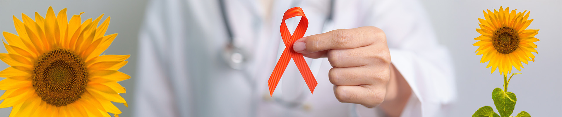Eine Frauenhand hält eine orangefarbene Schleife als Symbol der Solidarität mit Multiple-Sklerose-Betroffenen