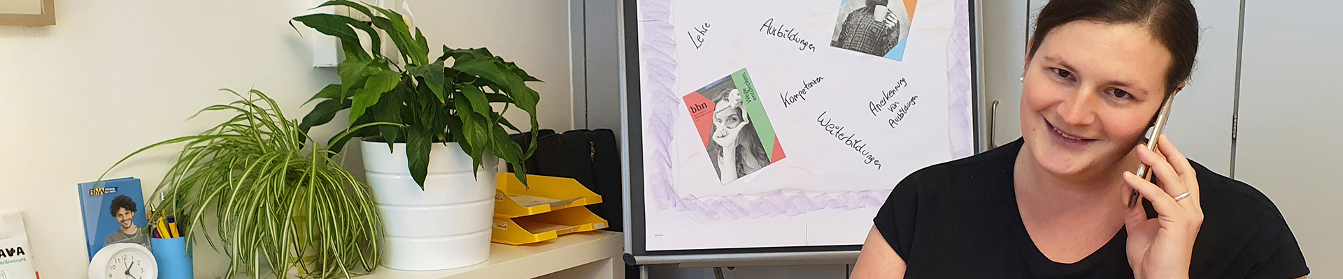 Bildungsberaterin Christa Sieder sitzt bei einem Tisch und telefoniert mit einer Rat-suchenden-Person und notiert sich etwas auf einem Schreibblock.