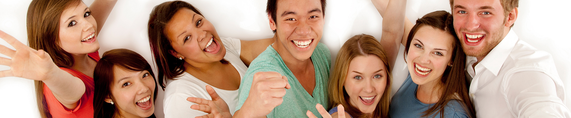 eine Gruppe junger Menschen, Männer und Frauen, verschiedener Hautfarben die in die Kamera lachen und die Hände in die Höhe halten.