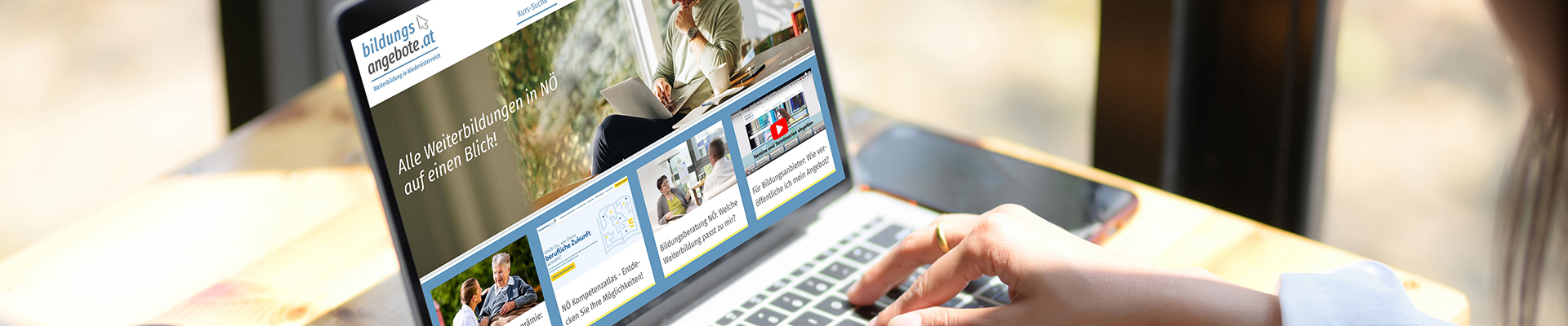 Aufgeklappter Laptop, auf dem Bildschirm sieht man die Startseite der Website "Bildungsangebote.at". Zwei Frauenhände tippen auf der Tastatur.