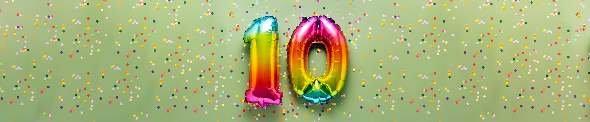 grüner Hintergrund mit Konfettis, im Vordergrund sieht man bunte aufgeblasene Luftballons in Form einer 10.